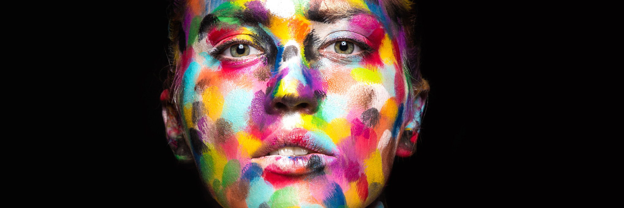 woman with her face painted in multi-colored spots
