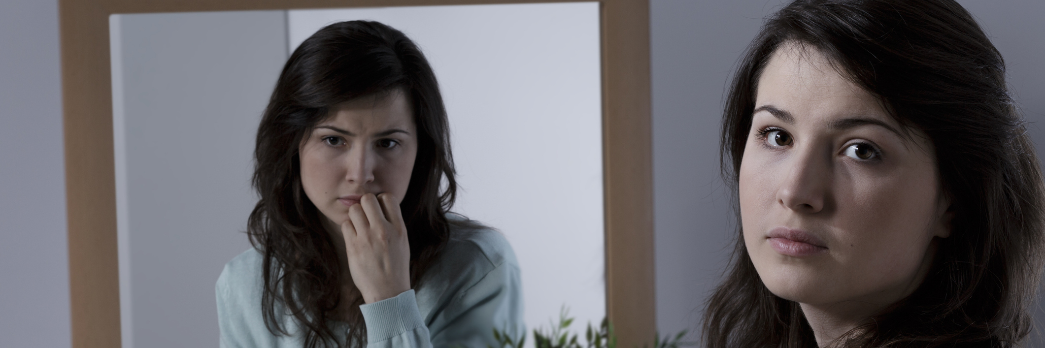 I Didn't Want to Be Defined By My Illness A woman's reflection, looking sad, while she looks at the camera.