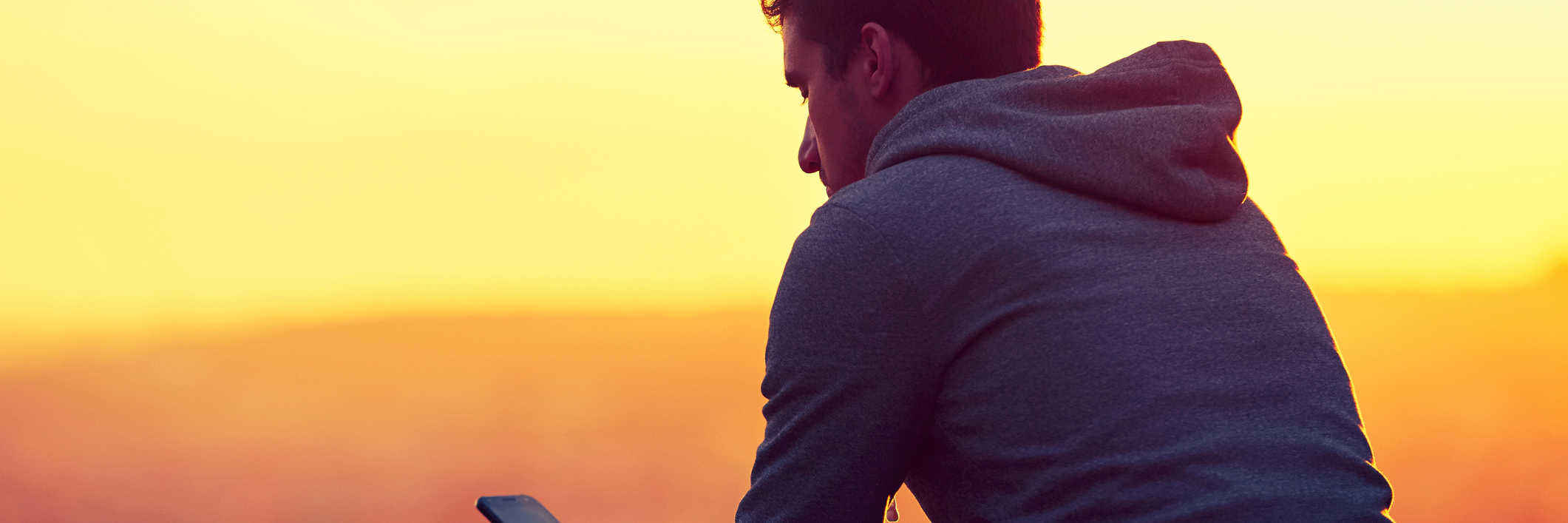 man sitting with phone at sunrise