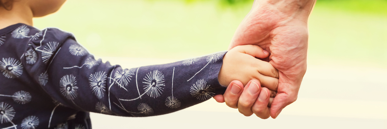 Toddler girl holding hands with her mother outside