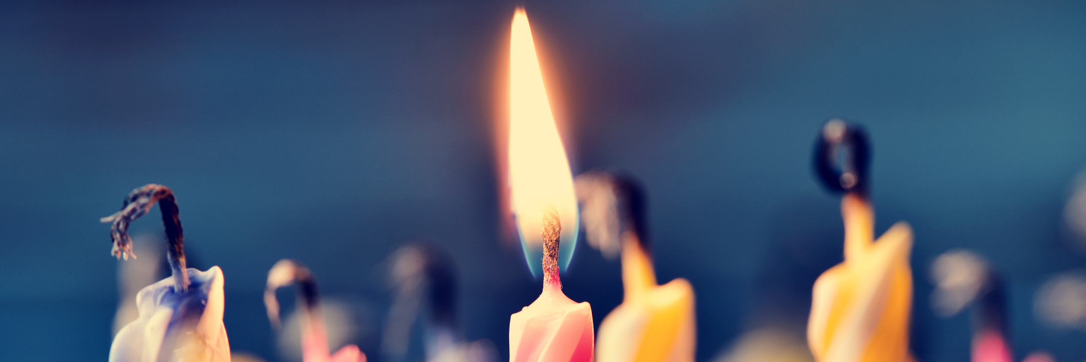 To My 14-Year-Old Self, Sitting in the Doctor's Office Close up on birthday cake candles, some blown out with one still lit.