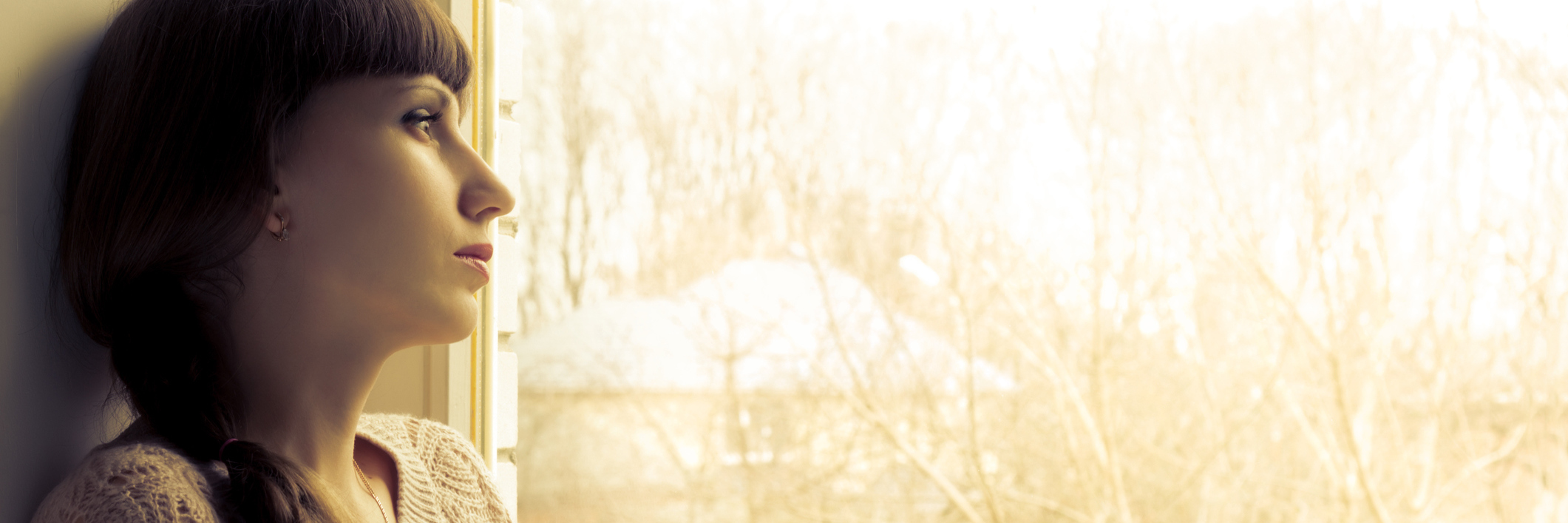 Chronic Illness: Being Unable to Finish College, Get a Degree and Work woman sitting next to a window reading a book and looking outside