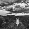 girl standing on mountain peak in black and white