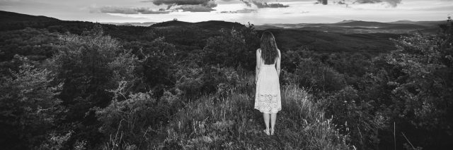 girl standing on mountain peak in black and white