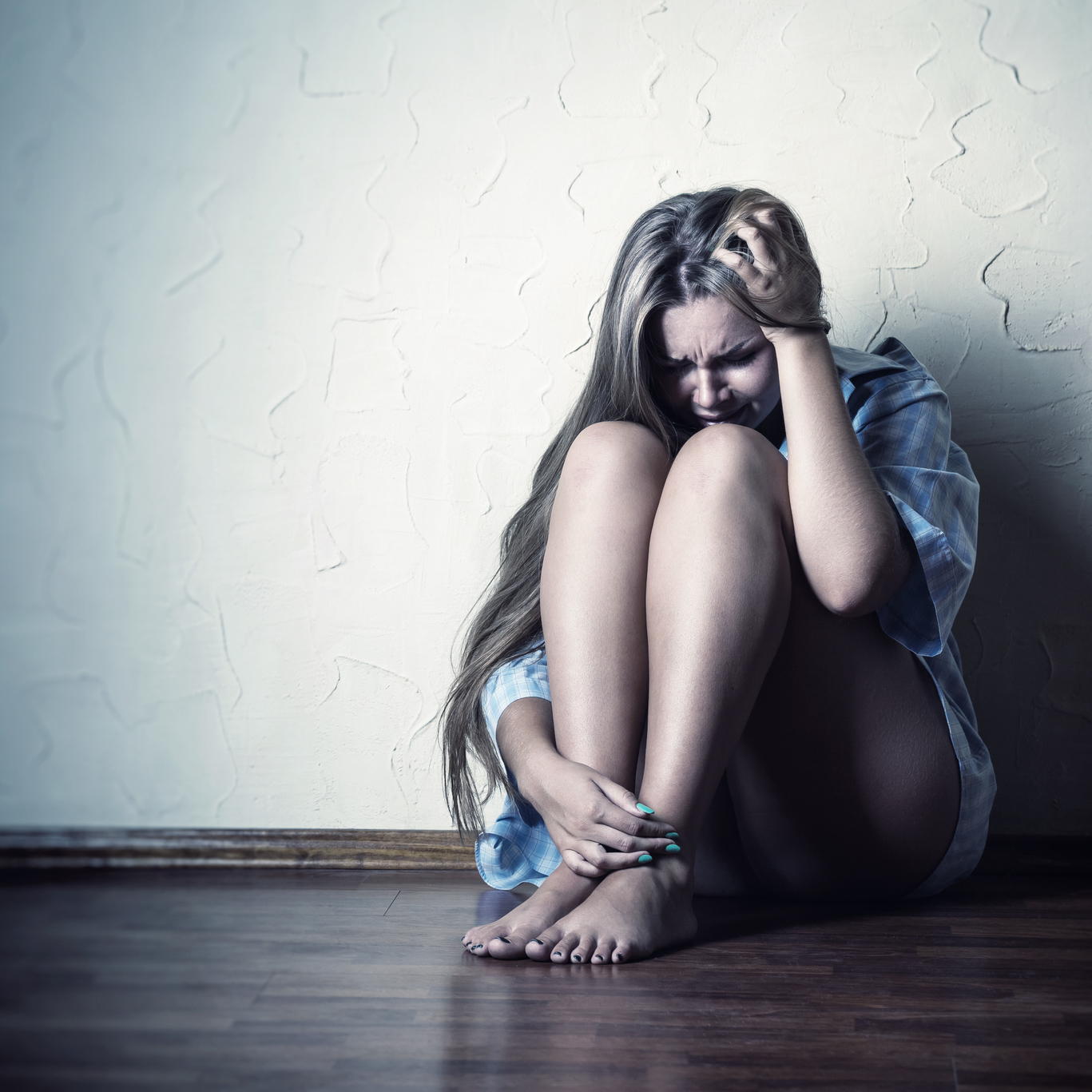 depression woman sitting in empty room hugging knees
