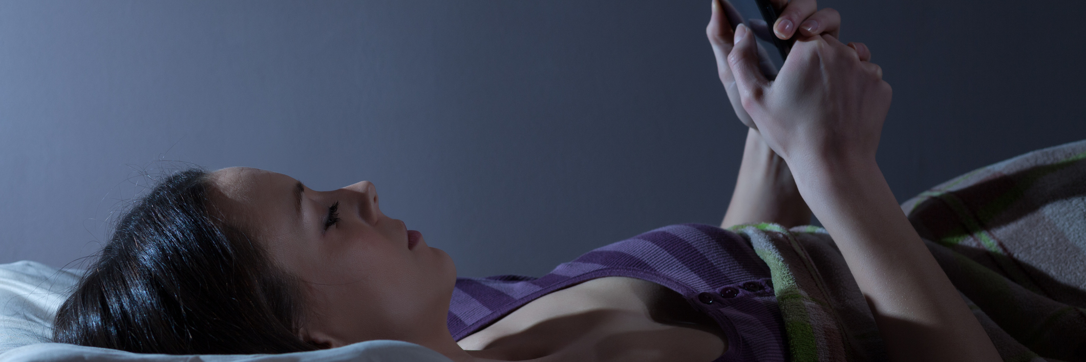 Not Being Able to Sleep Because of Chronic Pain woman lying in bed at night checking her phone