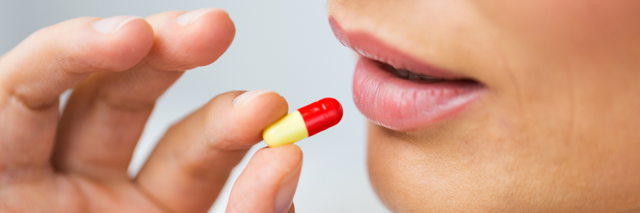 woman taking yellow and red pill close up