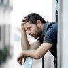 young man standing on balcony with depression