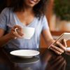 woman checking social media on her phone while drinking coffee