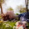 young girl lying on grass with daisies, smiling
