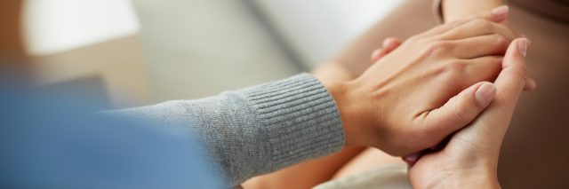 Close-up of person holding another person's hands in compassionate, comforting gesture