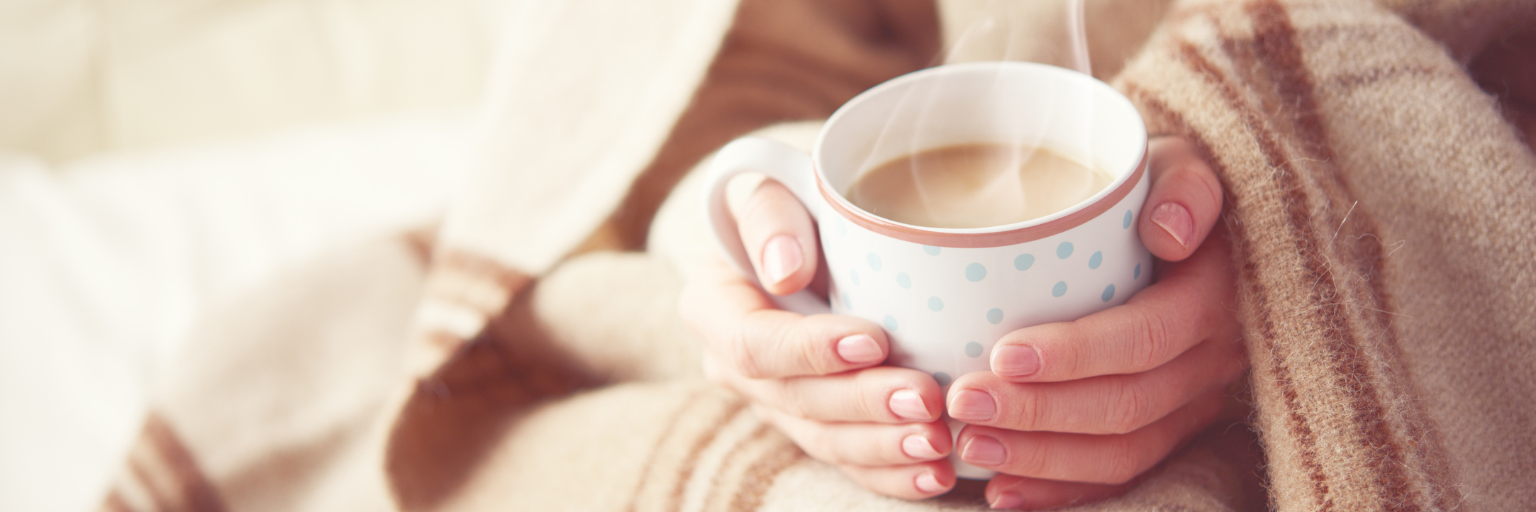 woman wrapped in a blanket and holding a mug of coffee
