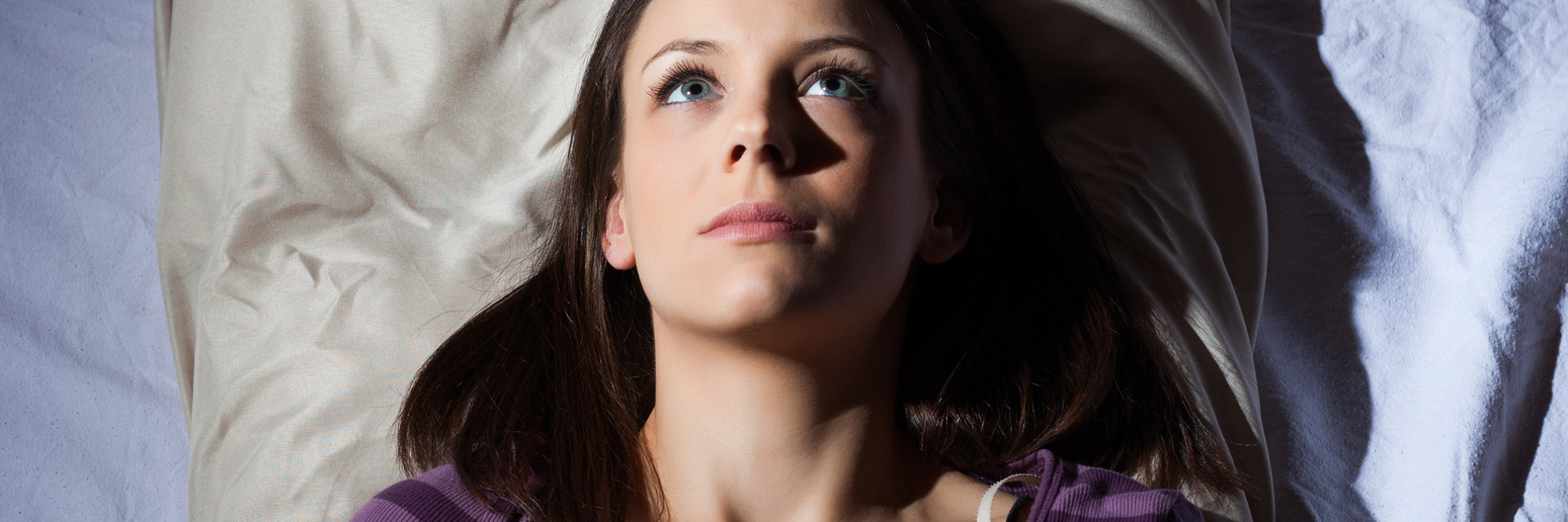 young woman lying in bed unable to sleep lost in thought