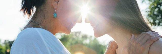 teen daughter with mature mother hugging in nature at sunset