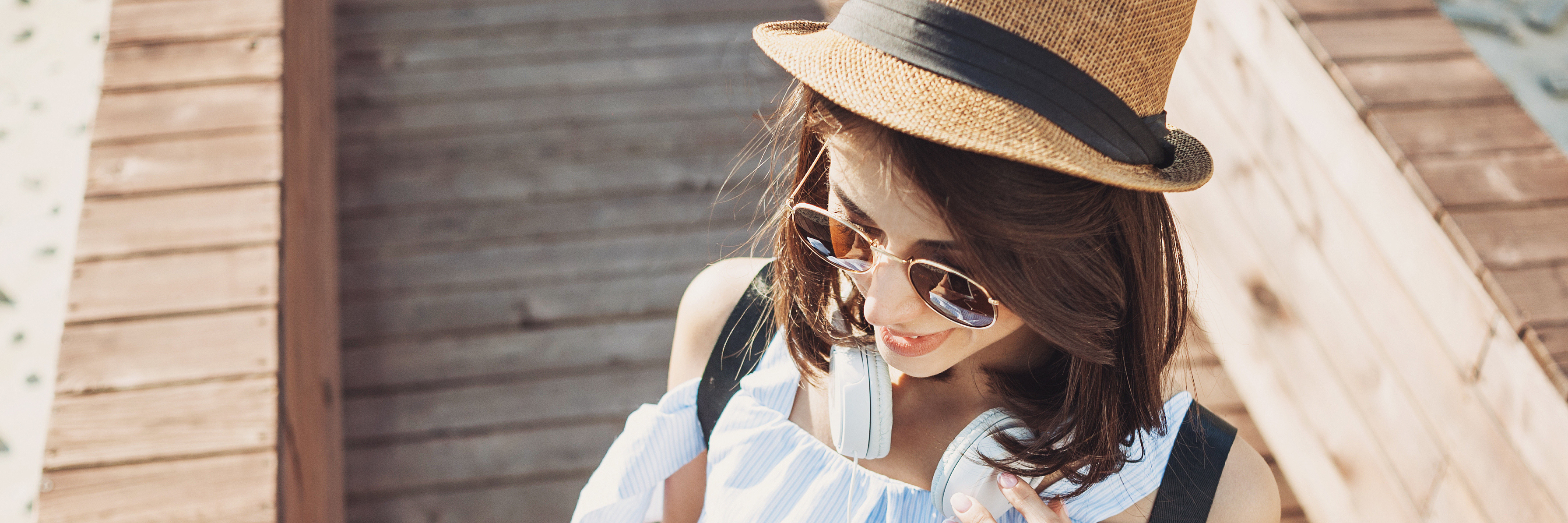 5 Ways I Deal With Sensory Overload From Multiple Sclerosis Woman standing outside, wearing a hat and sunglasses, while on her phone.