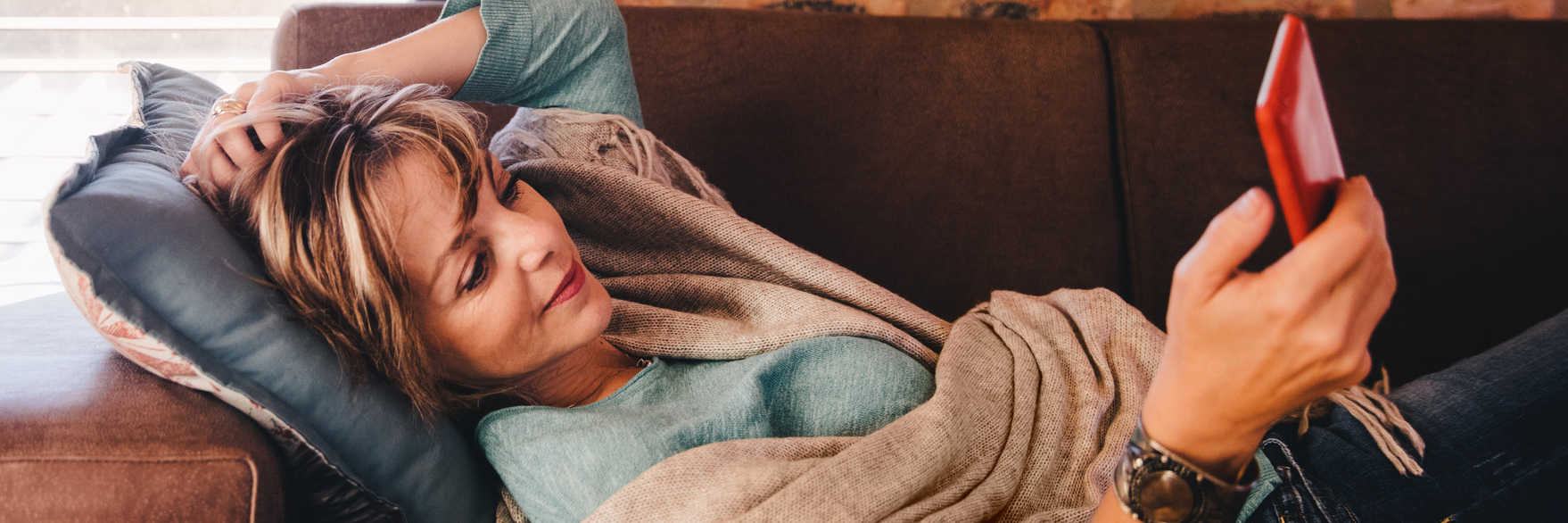 Fun, Creative Ways to Keep Yourself Occupied After Surgery woman lying on her couch looking at her phone