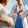 pregnant woman talking to doctor being shown something on clipboard chart