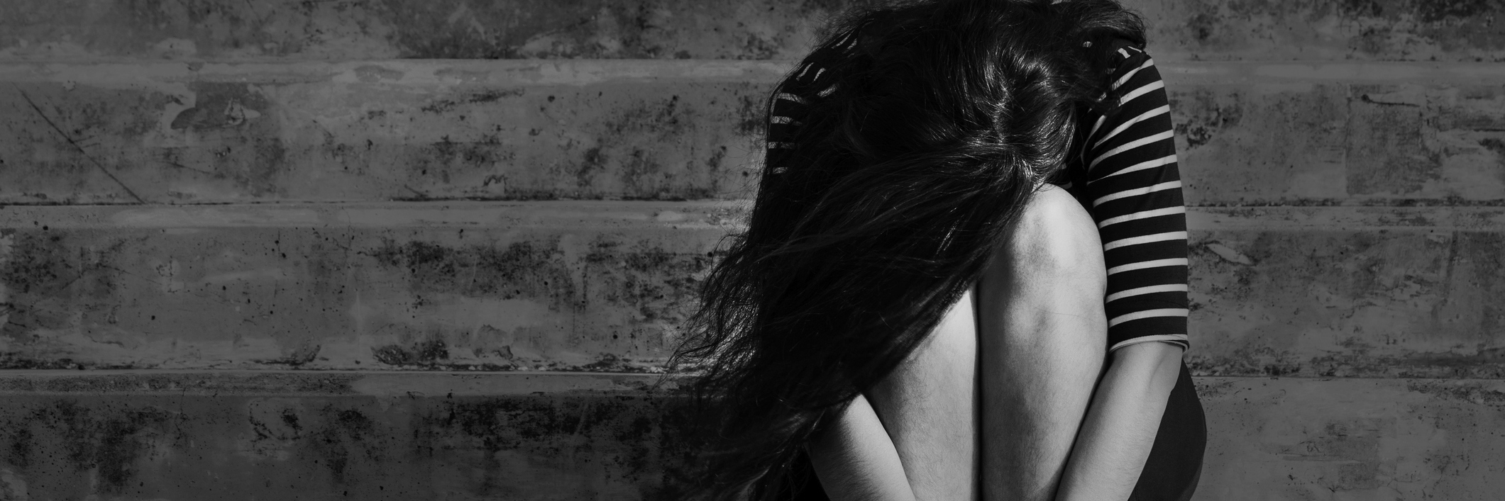 Feeling Grief, Depression, Anxiety After Recovering From Chronic Pain black and white photo of a woman sitting on a staircase with her head down crying