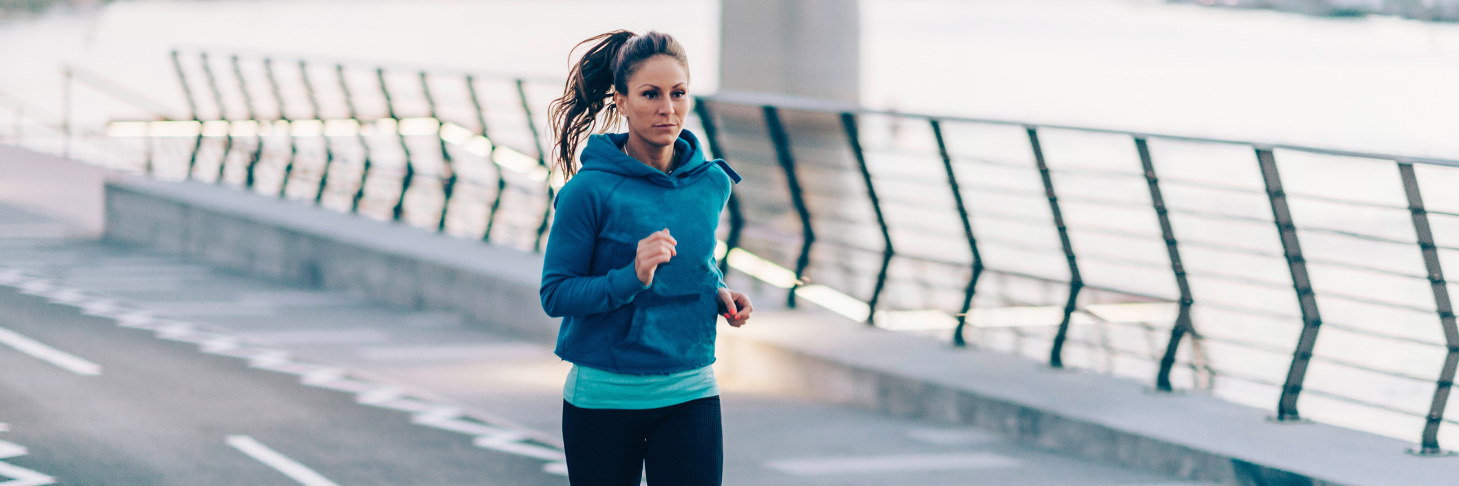 Working Out and Running to Help Manage POTS, Dysautonomia woman running on a street next to a river