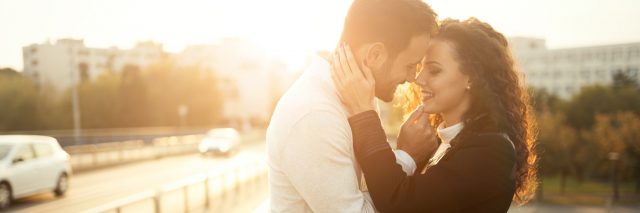 man and woman smiling at each other outdoors at sunset
