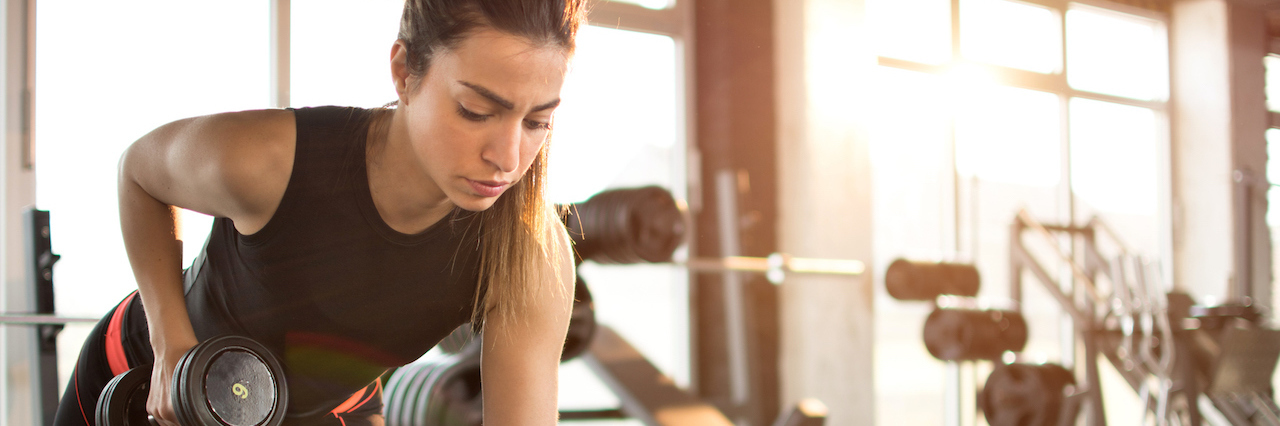 How Weightlifting Helps With Anxiety Fitness girl lifting dumbbell in the morning.