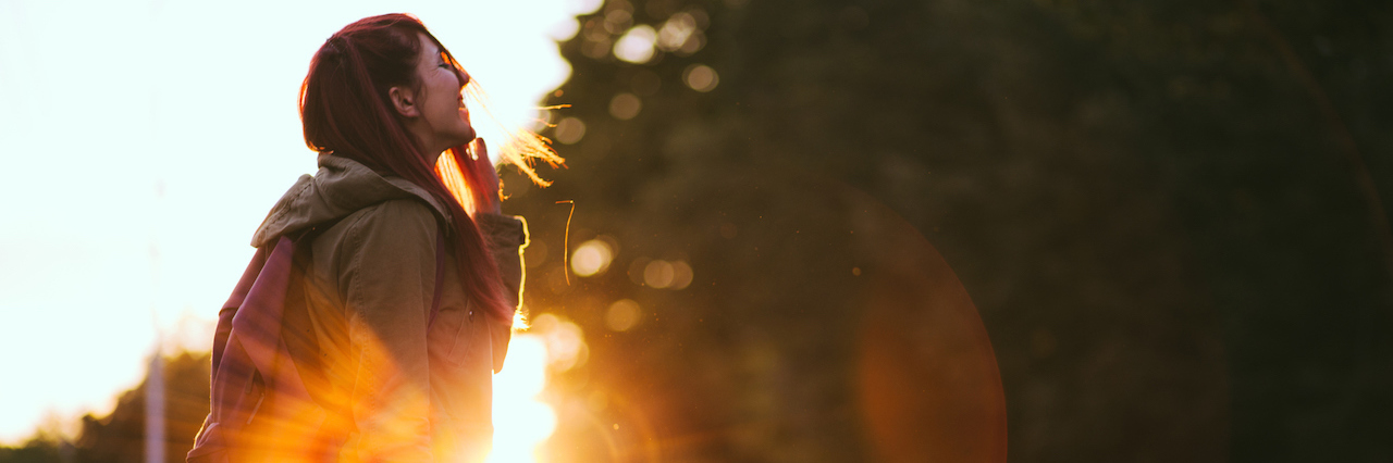 How I Fight Depression When It Keeps Me Down A woman standing outside looking up at sunset