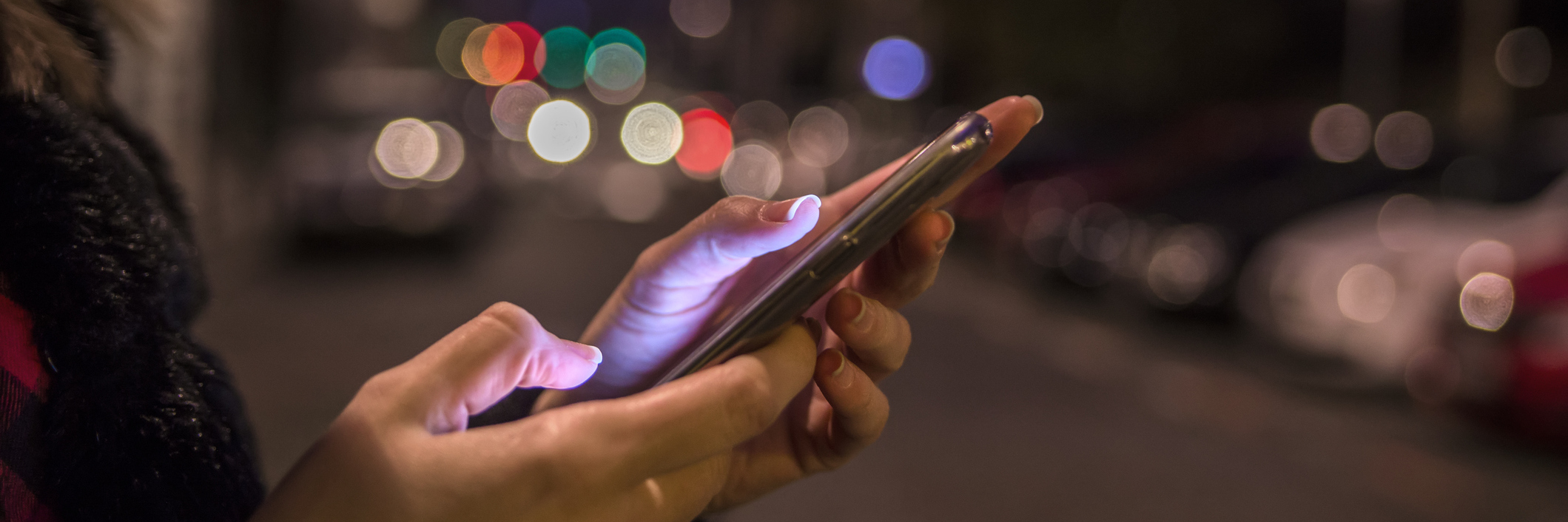 The Responses to a Text Message That Got Me Through My Anxiety Female hand holding touch screen mobile phone on blurred night lights background