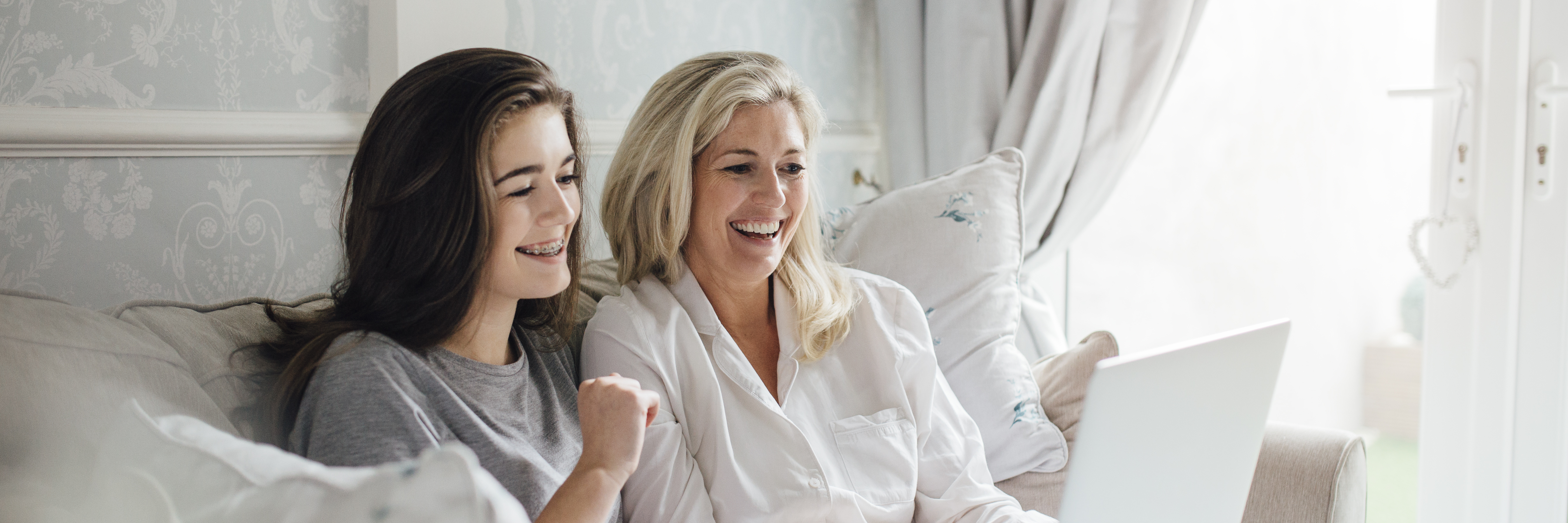 How I Knew My Mom Really Understood My Bipolar Disorder Mother and her daughter video calling someone on their laptop. They are smiling and waving at the screen.