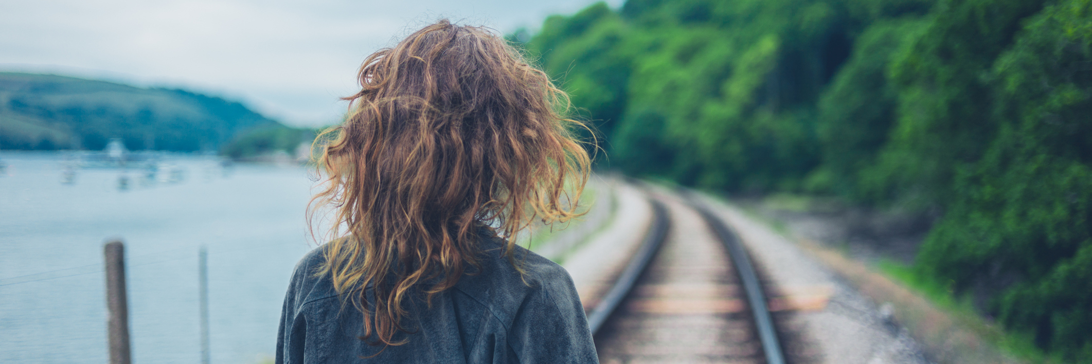 A young woman is walking on the railroad tracks