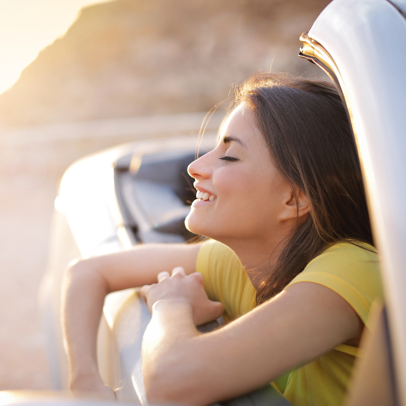 woman leaning out car window smiling and enjoy the air