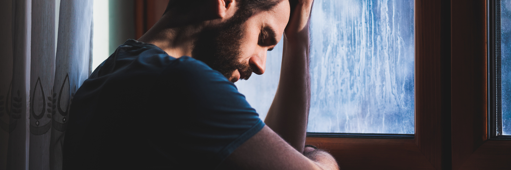 Living With OCD, Diagnosis and Intrusive Thoughts young man sitting at window with head on hand depression