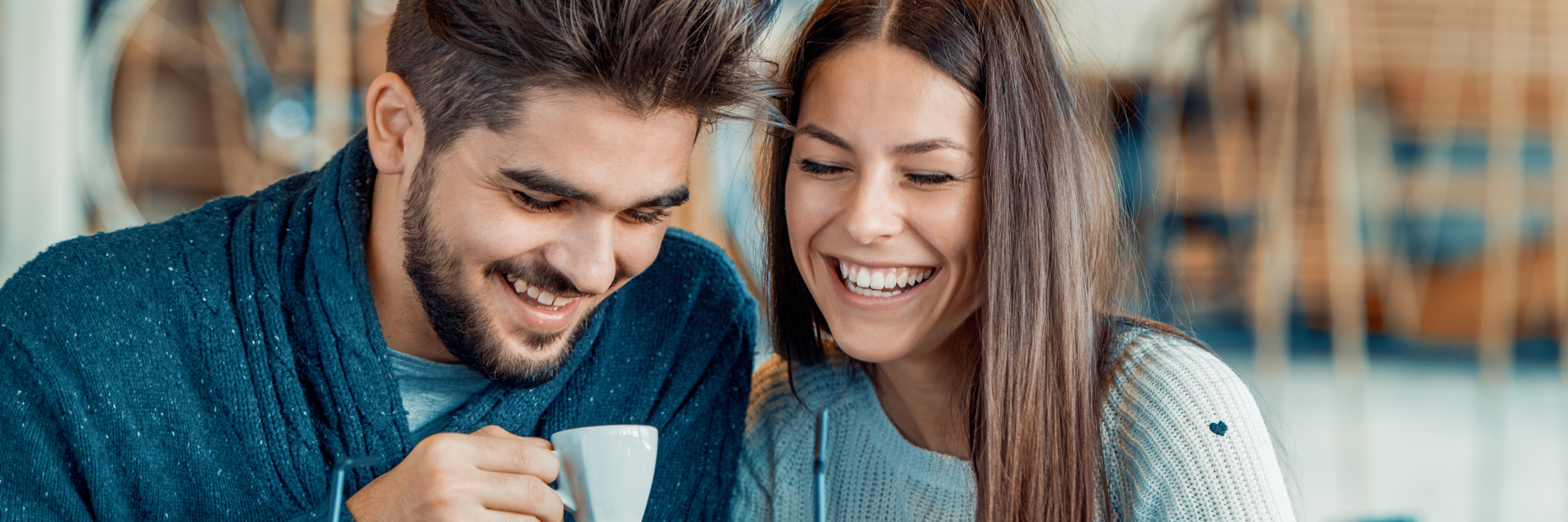 boyfriend and girlfriend sitting outside at a coffee shop laughing together