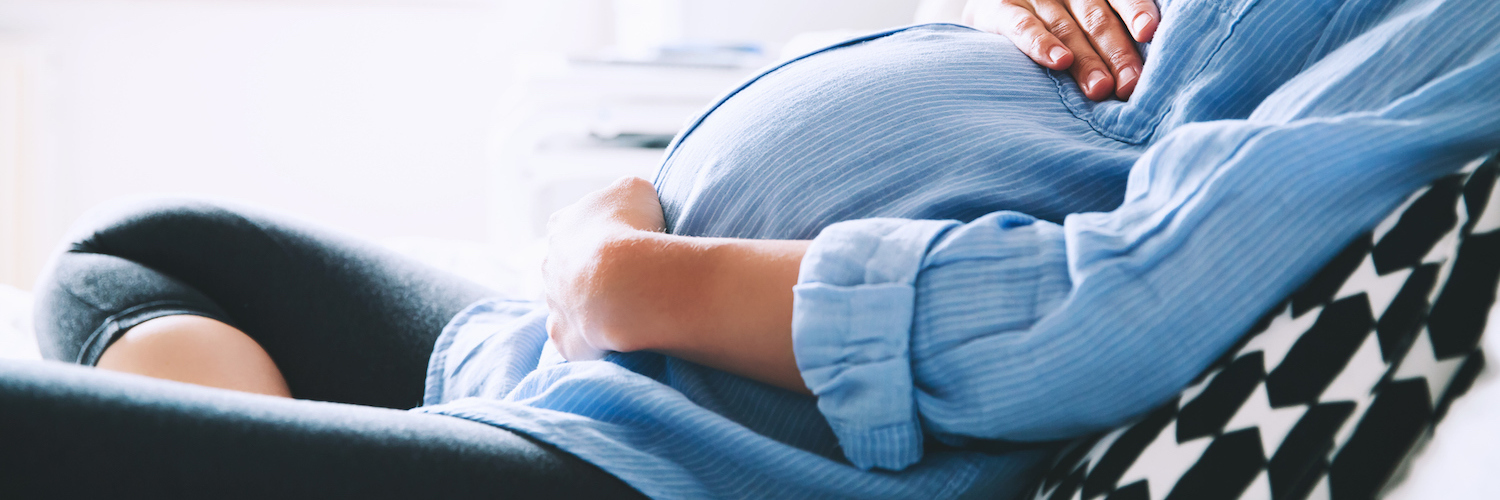 A Response to the Saying 'As Long as It's Healthy' Pregnant woman sitting, with her hands placed on her belly