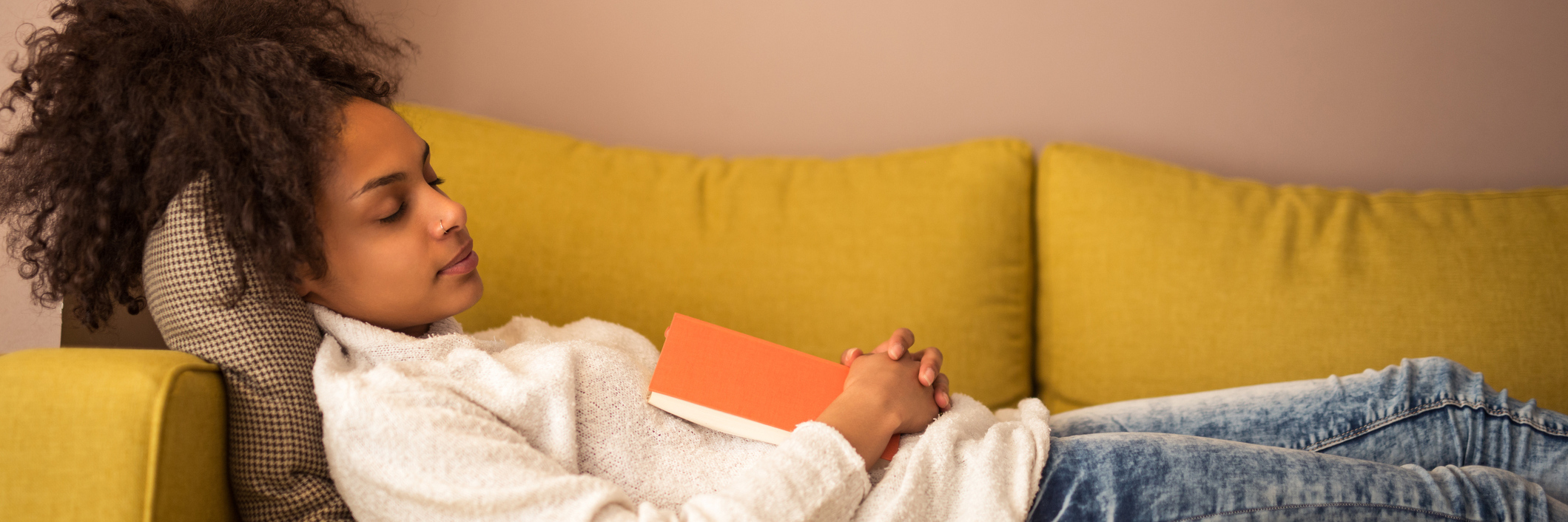 The Difficulty of Pacing With Chronic Fatigue Syndrome An young woman falling asleep on the couch with a book in hand.