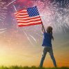 young girl waving an american flag in the sky with fireworks