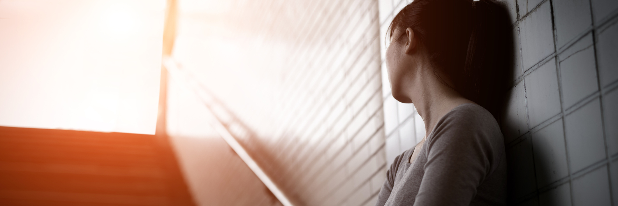 What I Mean When I Say I Don't Feel Ready for Mental Health Recovery depressed woman standing in underground looking at bright light up stairs