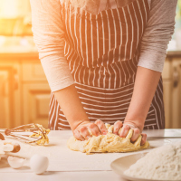 Woman kneading dough on kitchen table.