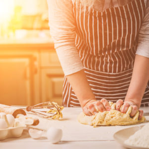 Woman kneading dough on kitchen table.