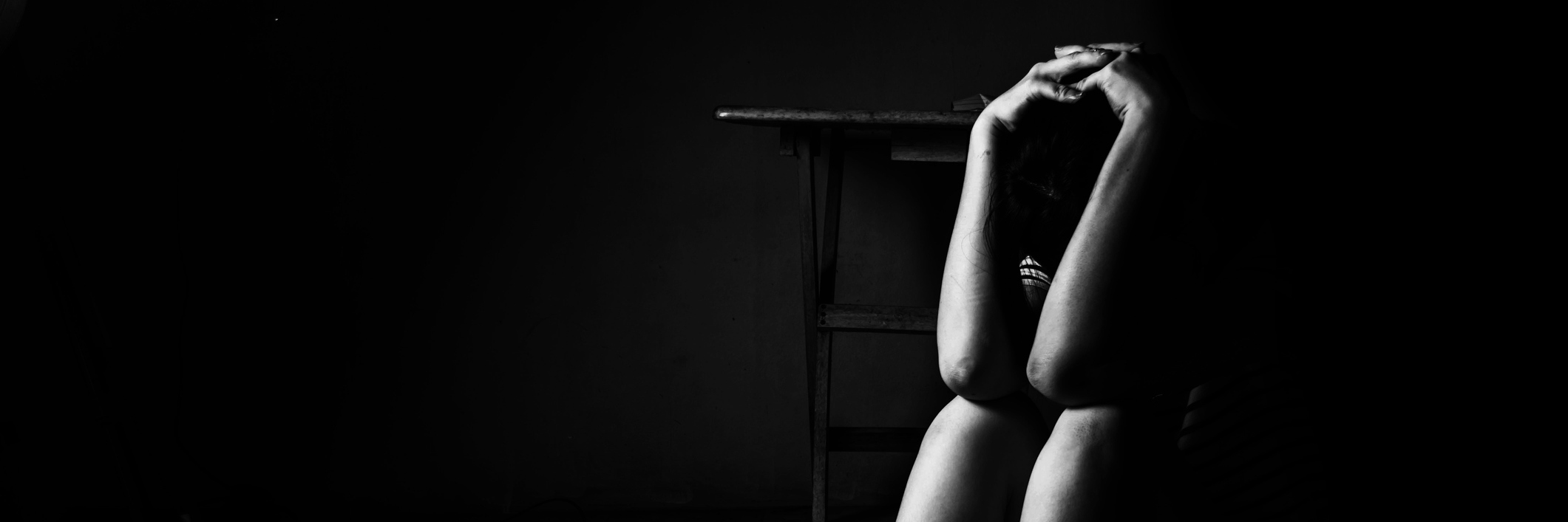 How Depression and Isolation Really Feel woman sitting on ground in darkness with arms raised to her head and elbows resting on knees