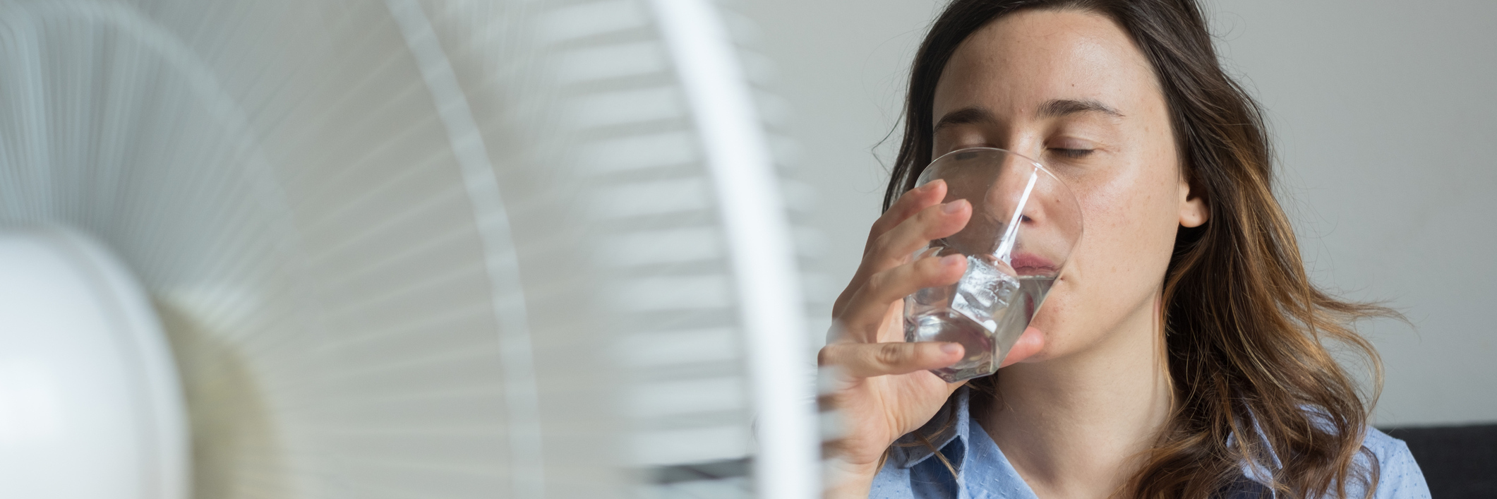 Heat Sensitivity, Chronic Illness: How to Stay Cool During Summer woman drinking water and sitting in front of a fan