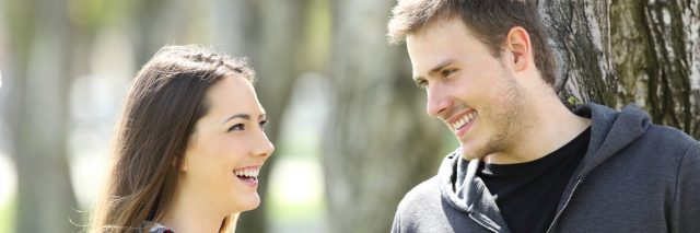 Two happy teen friends talking and looking each other in a park