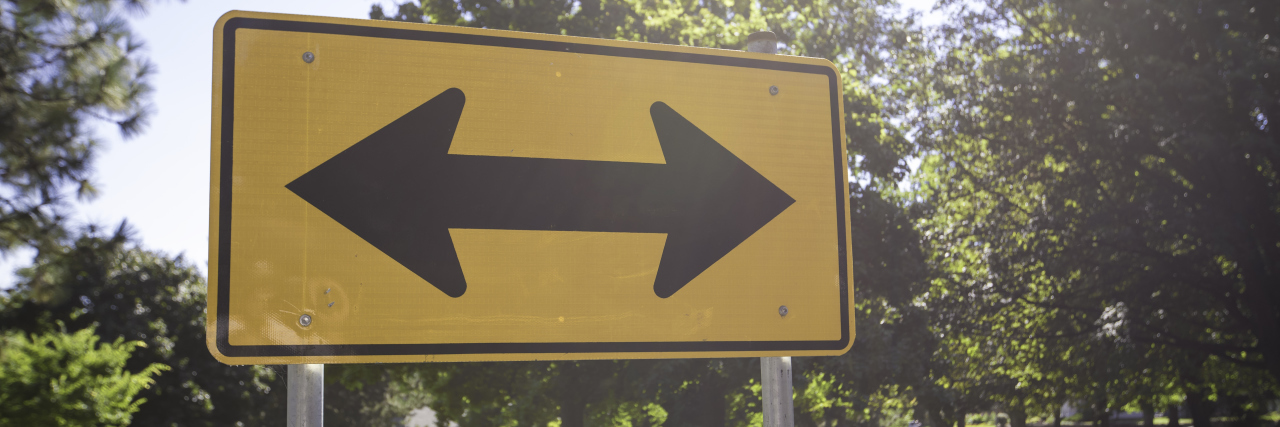 How to Promote Understanding Between Autistic and Neurotypical People Two-way street sign with trees in background.