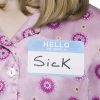 girl wearing pajamas with a nametag on her chest that says 'my name is 'sick''