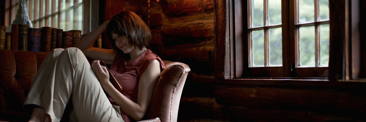 Woman sitting on sofa, reading book