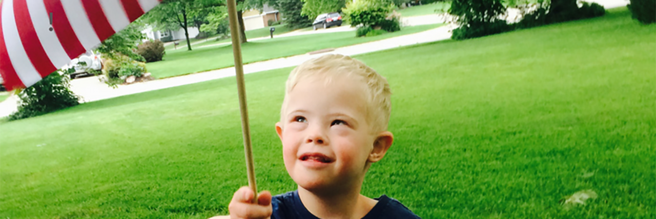 Medicaid Is Essential for My Son With Down Syndrome Troy, a little boy with Down syndrome holding an American flag.
