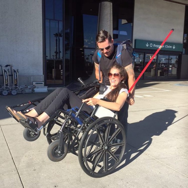 man helping a woman in a wheelchair do a wheelie