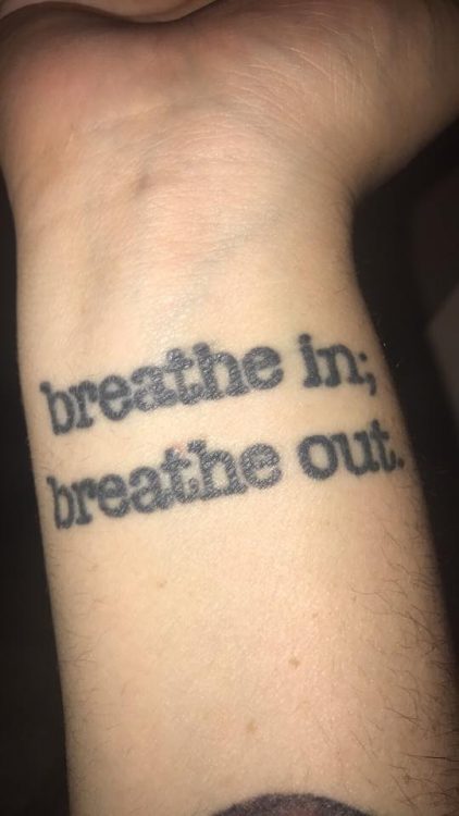 breathe in, breathe out words tattooed on wrist