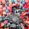 woman rising motorcycle behind background of pills