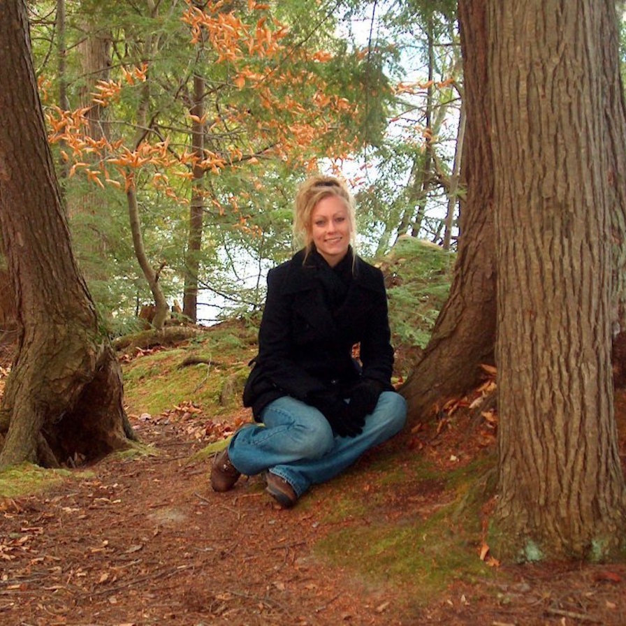 woman sitting in the forest next to a tree