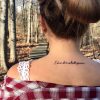 girl standing in woods with back to camera and tattoo on her back saying "this too shall pass"
